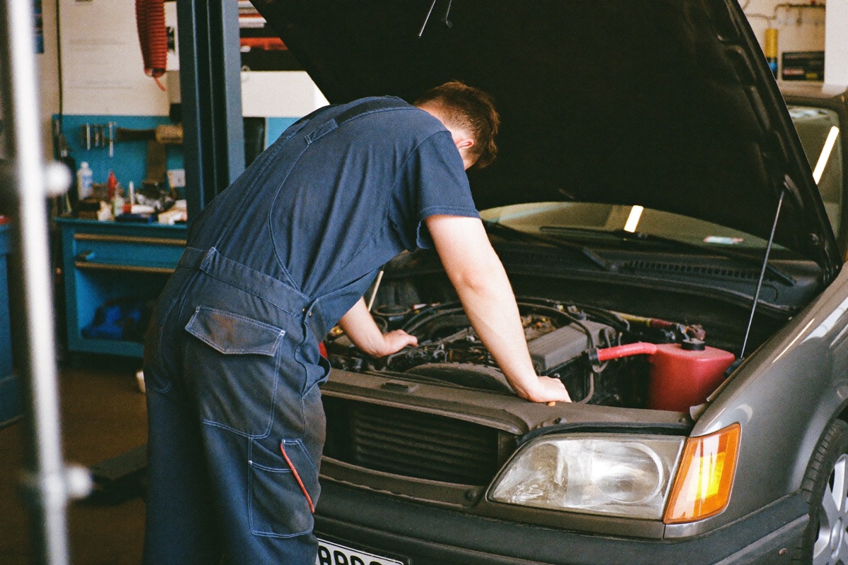 Mechanic working on a car engine under the open hood in a repair workshop